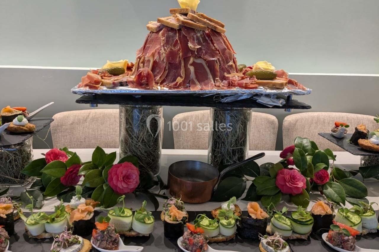 Location salle Bordeaux (Gironde) - Restaurant Le Family #32 Plateau de charcuterie en forme de montagne entouré de bouchées variées, décoré de fleurs et de verdure.