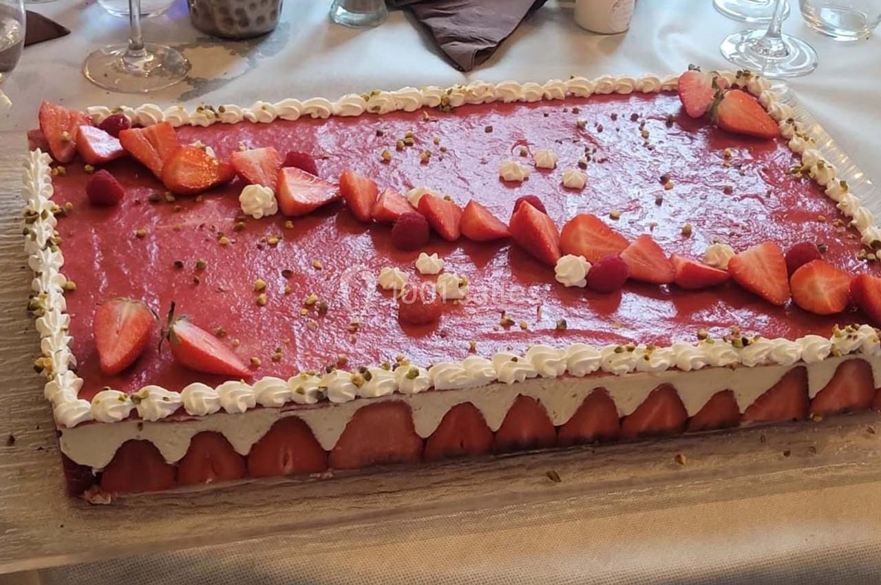 Location salle Bordeaux (Gironde) - Restaurant Le Family #33 Gâteau rectangulaire décoré de fraises, framboises, chantilly et éclats de pistaches sur une table dressée.