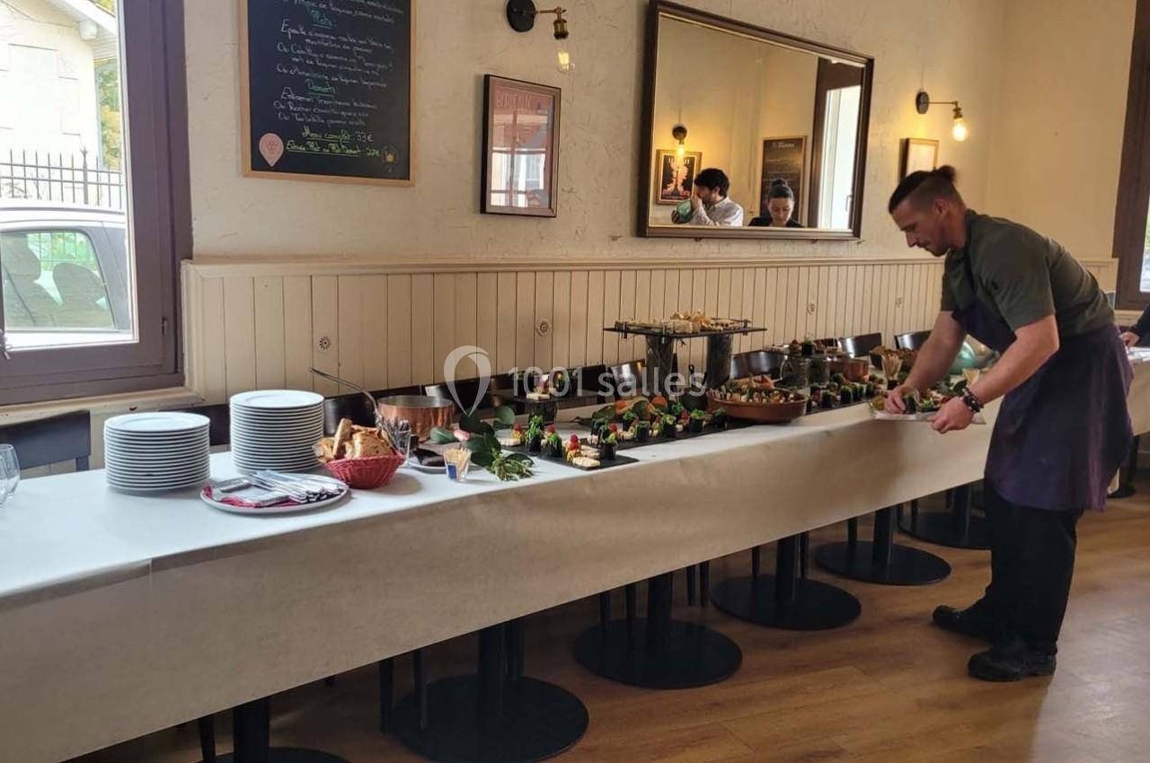 Location salle Bordeaux (Gironde) - Restaurant Le Family #16 Un buffet avec des plats variés, des assiettes empilées et un homme en tablier disposant des aliments.
