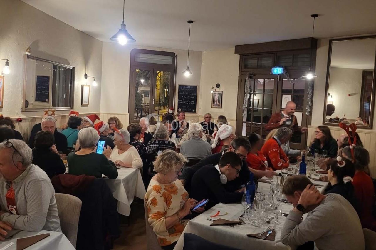 Location salle Bordeaux (Gironde) - Restaurant Le Family #21 Groupe de personnes d'âges variés partageant un repas dans un restaurant chaleureux, décoré pour les fêtes.