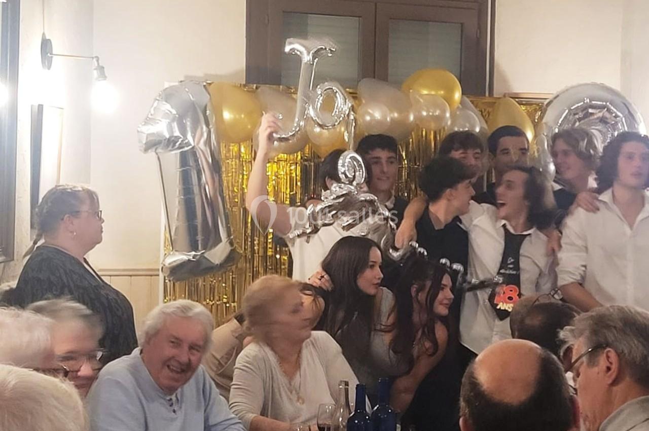 Location salle Bordeaux (Gironde) - Restaurant Le Family #17 Un groupe de jeunes et d'adultes réunis lors d'une fête, avec des ballons dorés et argentés en arrière-plan.