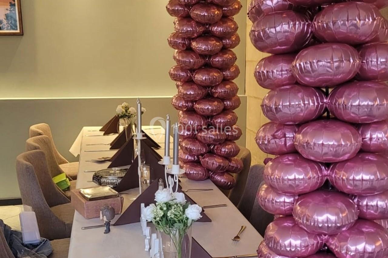 Location salle Bordeaux (Gironde) - Restaurant Le Family #3 Table décorée avec des bougies, des fleurs blanches et des colonnes de ballons roses dans une salle élégante.
