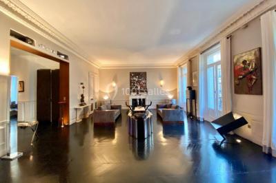 Table ronde en métal noir avec chandelier et chaises, placée sur un balcon avec vue sur une façade d'immeuble haussmannien.