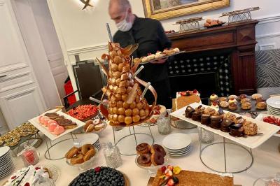 Table ronde en métal noir avec chandelier et chaises, placée sur un balcon avec vue sur une façade d'immeuble haussmannien.