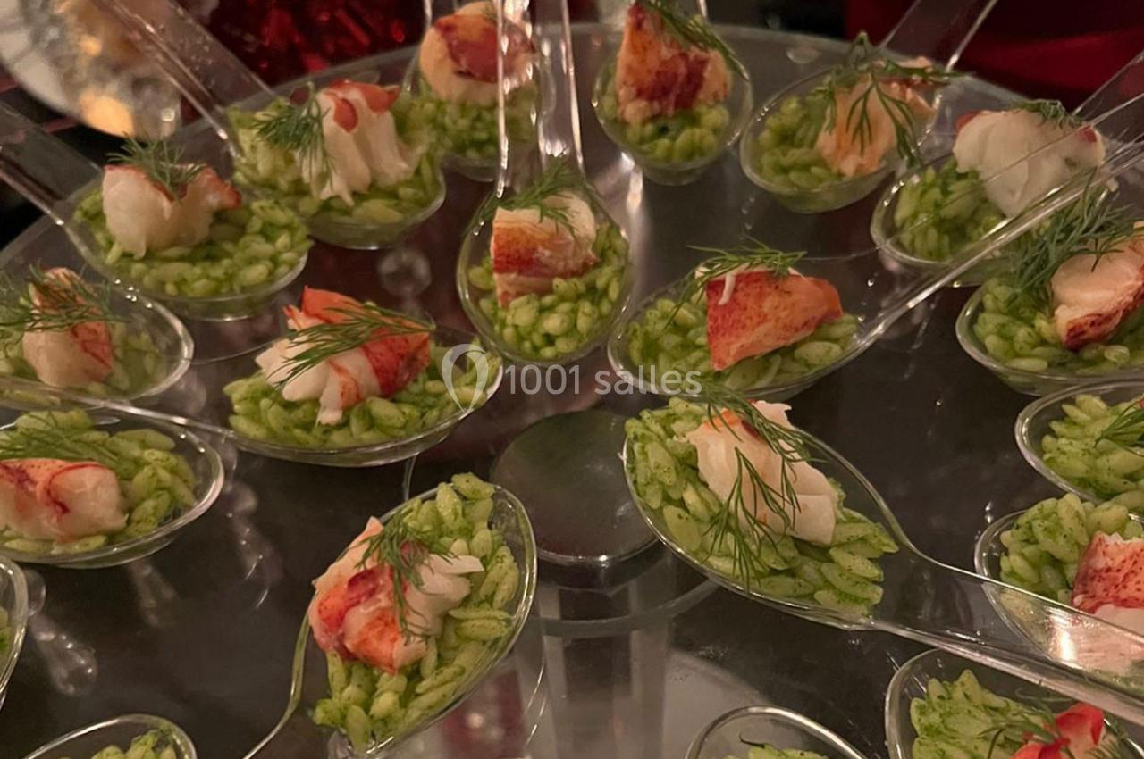 Cuillères apéritives garnies de risotto vert et morceaux de homard, décorées de brins d'aneth.