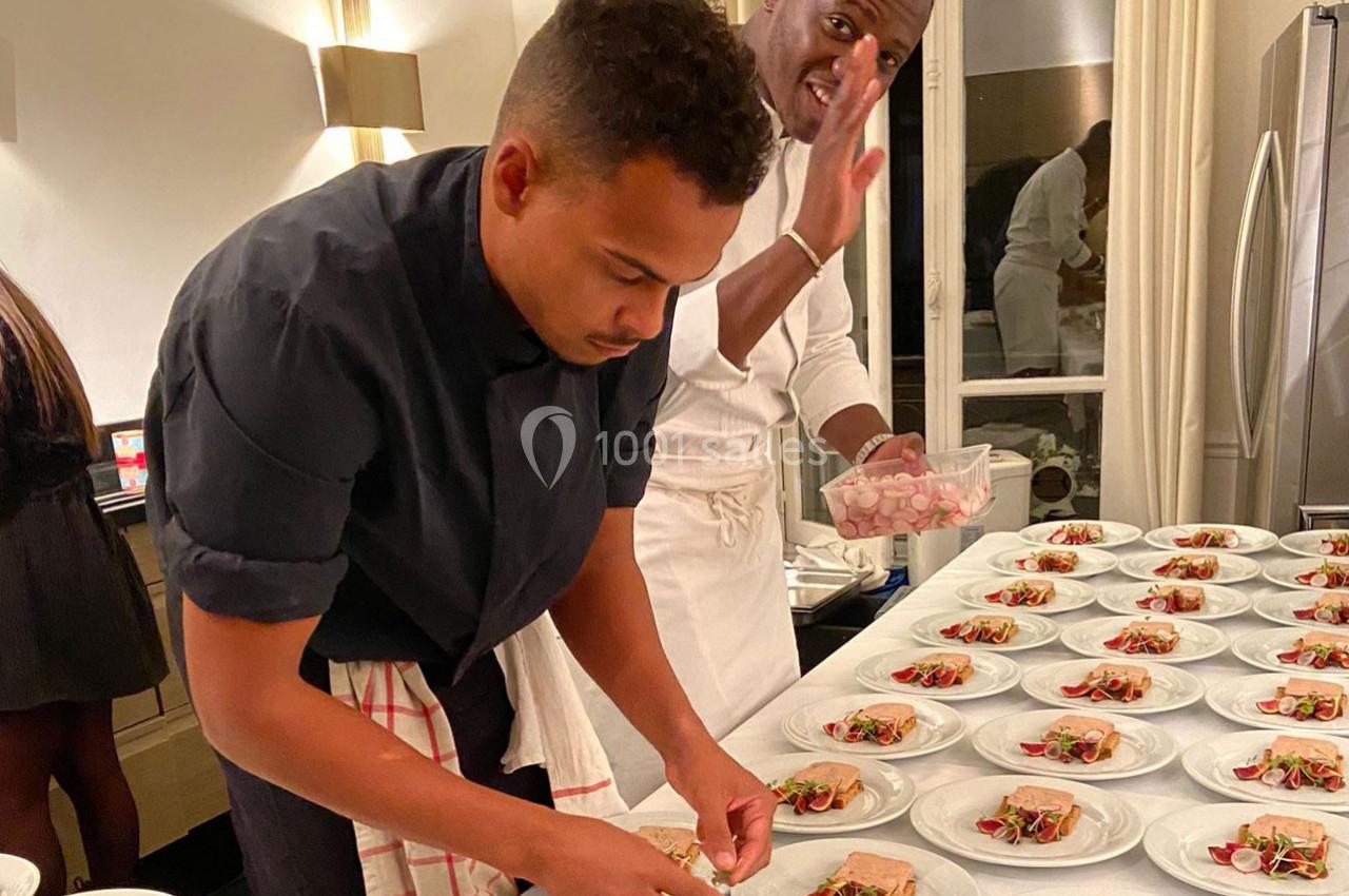 Deux chefs préparent et dressent des assiettes avec soin dans une cuisine bien éclairée.