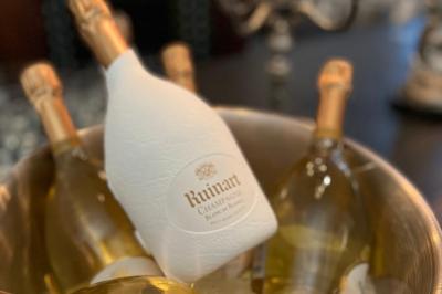Table ronde en métal noir avec chandelier et chaises, placée sur un balcon avec vue sur une façade d'immeuble haussmannien.