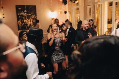 Table ronde en métal noir avec chandelier et chaises, placée sur un balcon avec vue sur une façade d'immeuble haussmannien.