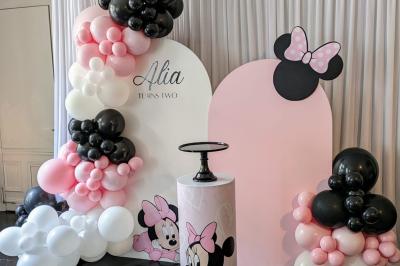 Table ronde en métal noir avec chandelier et chaises, placée sur un balcon avec vue sur une façade d'immeuble haussmannien.