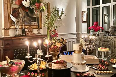 Table ronde en métal noir avec chandelier et chaises, placée sur un balcon avec vue sur une façade d'immeuble haussmannien.