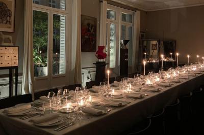 Table ronde en métal noir avec chandelier et chaises, placée sur un balcon avec vue sur une façade d'immeuble haussmannien.