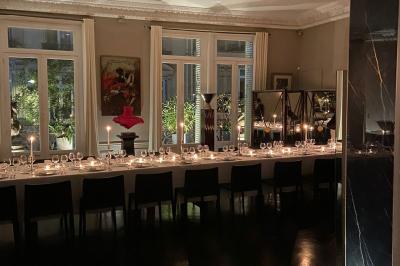 Table ronde en métal noir avec chandelier et chaises, placée sur un balcon avec vue sur une façade d'immeuble haussmannien.