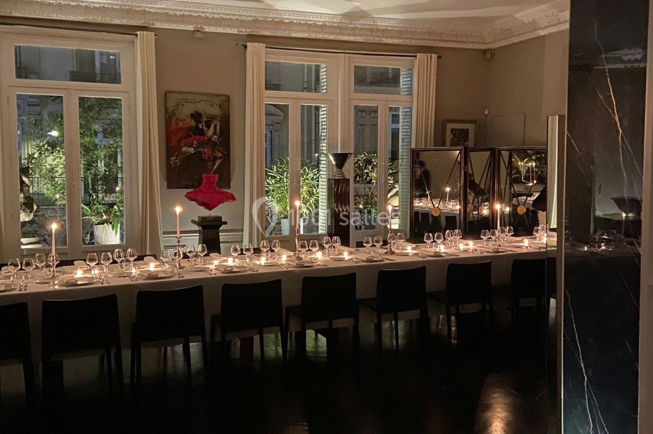 Grande table élégamment dressée dans une salle à manger avec bougies allumées, baignée par une lumière tamisée.