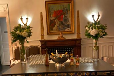 Table ronde en métal noir avec chandelier et chaises, placée sur un balcon avec vue sur une façade d'immeuble haussmannien.