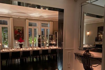 Table ronde en métal noir avec chandelier et chaises, placée sur un balcon avec vue sur une façade d'immeuble haussmannien.