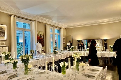 Table ronde en métal noir avec chandelier et chaises, placée sur un balcon avec vue sur une façade d'immeuble haussmannien.