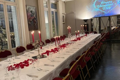 Table ronde en métal noir avec chandelier et chaises, placée sur un balcon avec vue sur une façade d'immeuble haussmannien.