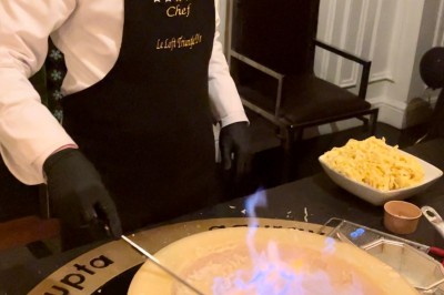 Table ronde en métal noir avec chandelier et chaises, placée sur un balcon avec vue sur une façade d'immeuble haussmannien.