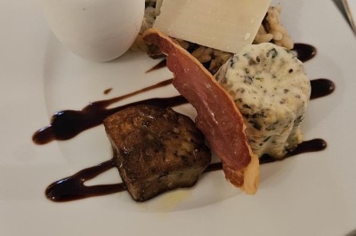 Table ronde en métal noir avec chandelier et chaises, placée sur un balcon avec vue sur une façade d'immeuble haussmannien.
