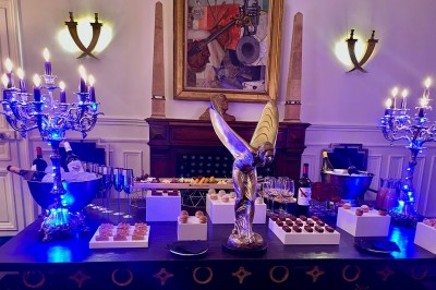 Une statue en pierre orne un balcon avec vue sur des immeubles anciens dans un environnement urbain.