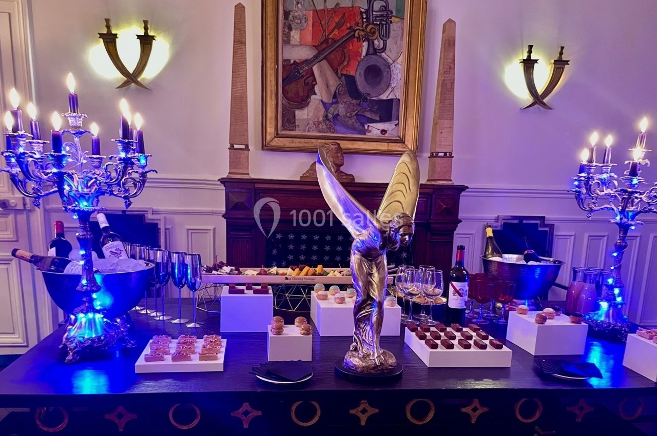 Table décorée avec des chandeliers, une sculpture dorée et un buffet de desserts variés dans un cadre élégant.
