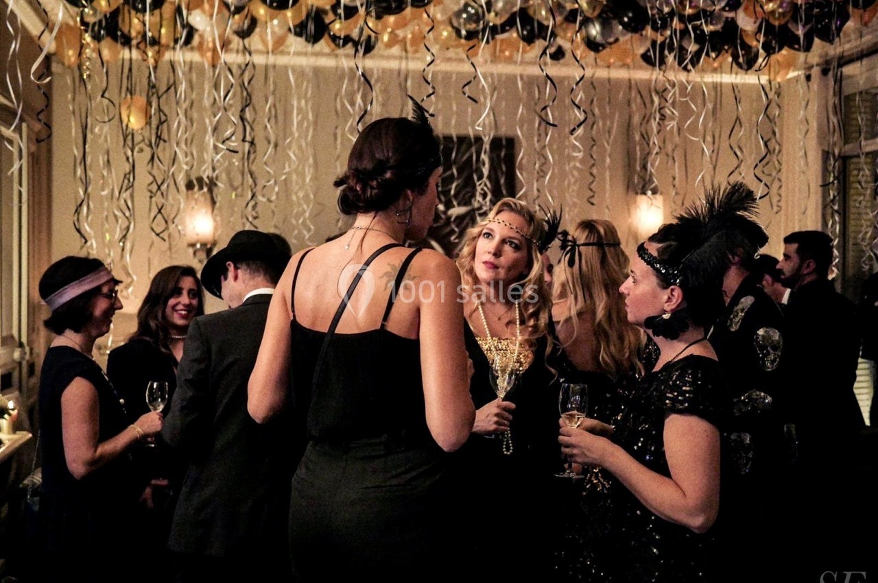 Location salle Paris 8 (Paris) - Le Loft Triangle d'Or Champs-Élysées #35 Personnes en tenue de soirée discutant dans une salle décorée de ballons et de guirlandes suspendues.