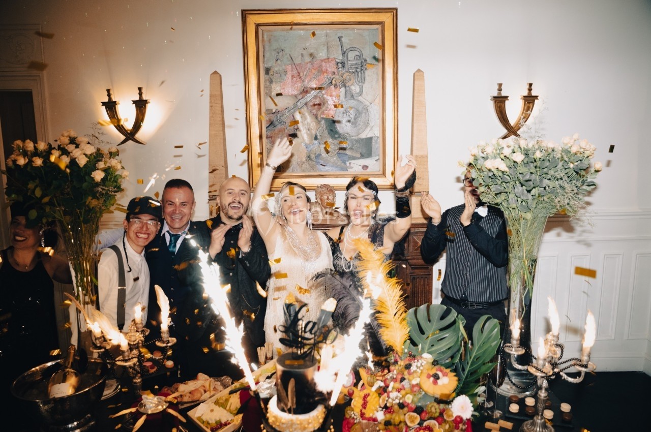 Location salle Paris 8 (Paris) - Le Loft Triangle d'Or Champs-Élysées #39 Des personnes célèbrent joyeusement dans une salle décorée, entourées de fleurs, de bougies et de confettis.