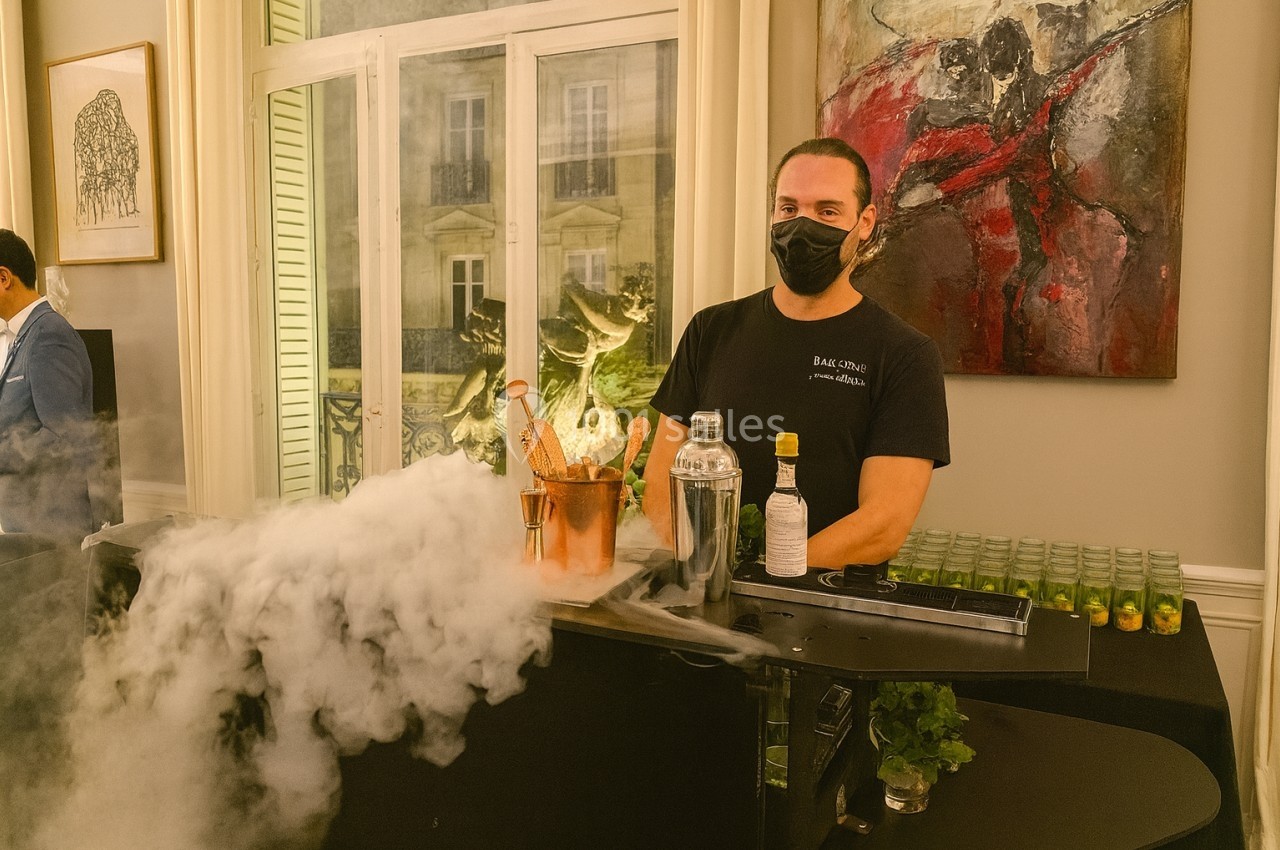 Location salle Paris 8 (Paris) - Le Loft Triangle d'Or Champs-Élysées #43 Un barman masqué prépare des cocktails avec de la glace sèche produisant de la fumée, dans un cadre intérieur élégant.
