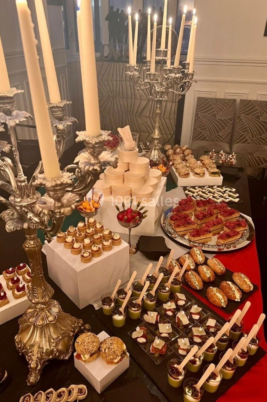 Table garnie de desserts variés, bougies sur chandeliers en argent, ambiance élégante et festive.