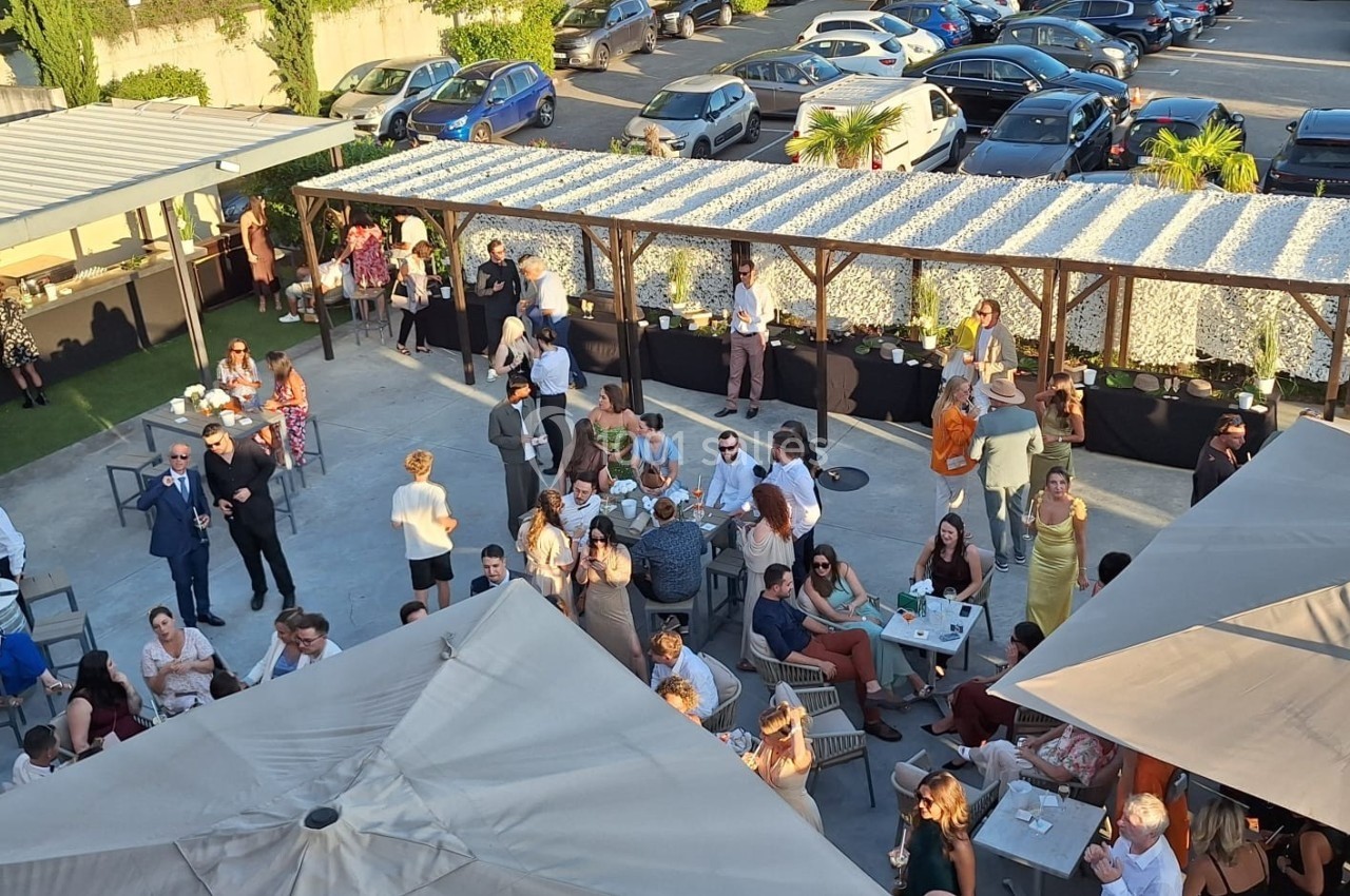 Vue aérienne d'une terrasse animée avec des groupes de personnes discutant et profitant d'un événement en plein air.