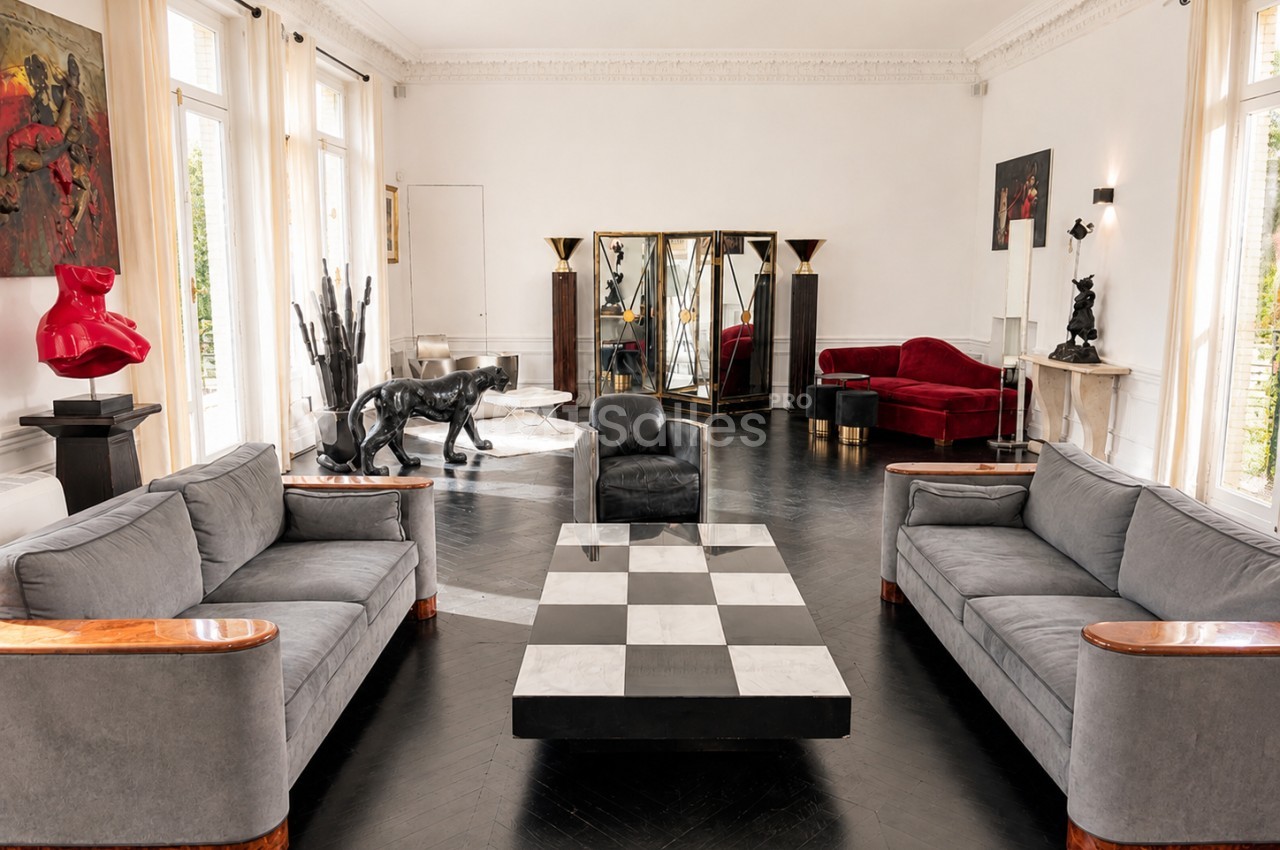 Salon spacieux avec mobilier design, table basse à motif damier, canapés gris et œuvres d'art contemporaines.
