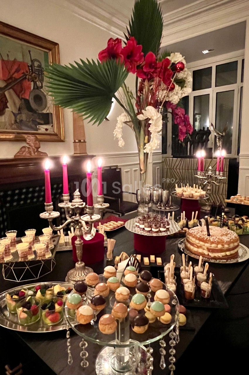 Table décorée avec des chandeliers et un assortiment de desserts variés, dans un intérieur élégant et chaleureux.