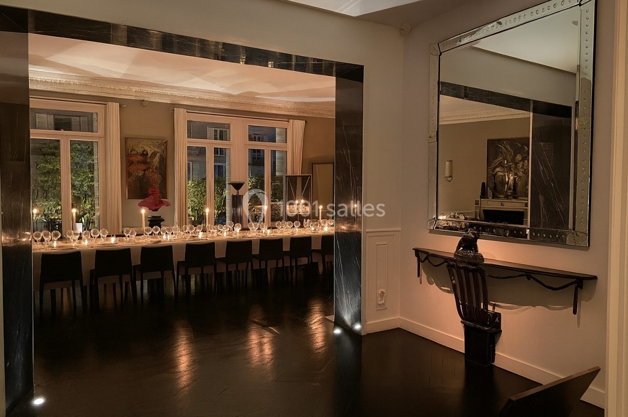 Salle à manger élégante avec une longue table dressée, éclairée par des bougies, et un grand miroir mural.