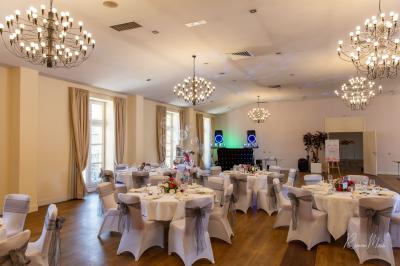 Table de réception élégamment dressée avec menu, verres, et centre de table floral composé de roses rouges et blanches.