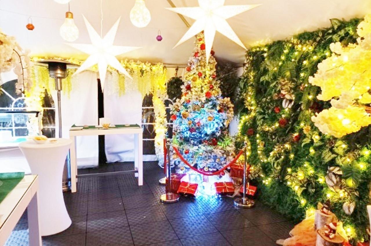 Décoration festive dans une tente illuminée avec un sapin de Noël coloré, guirlandes lumineuses et ornements.