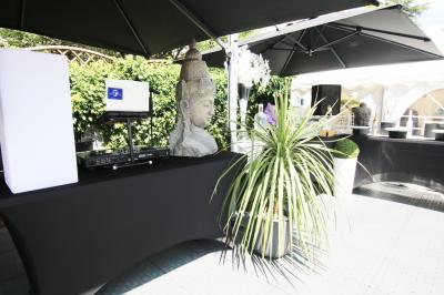 Salle de réception décorée en noir et blanc avec tables dressées, chaises blanches et lanternes suspendues.
