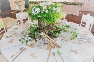 Salle de réception décorée en noir et blanc avec tables dressées, chaises blanches et lanternes suspendues.