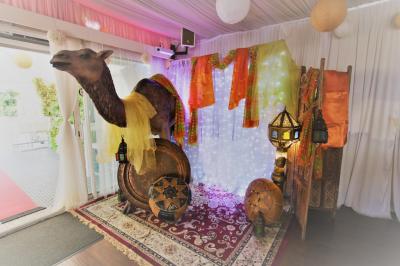 Salle de réception décorée en noir et blanc avec tables dressées, chaises blanches et lanternes suspendues.