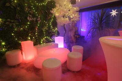 Salle de réception décorée en noir et blanc avec tables dressées, chaises blanches et lanternes suspendues.