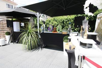 Salle de réception décorée en noir et blanc avec tables dressées, chaises blanches et lanternes suspendues.