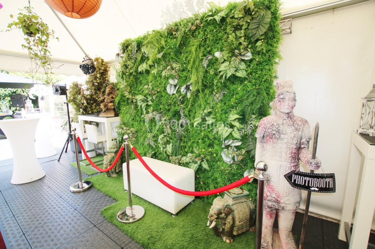 Mur végétal décoratif avec statue, éléphant ornemental et espace photobooth délimité par une corde rouge.