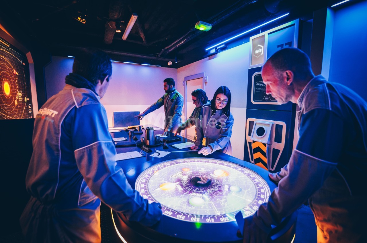 Des personnes en combinaison analysent une table interactive lumineuse dans une salle au décor futuriste.
