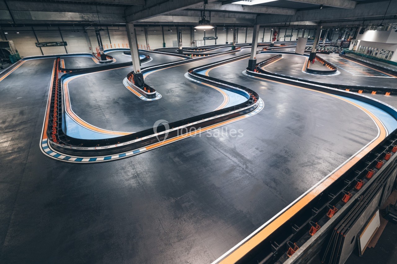 Piste de karting intérieure avec virages serrés, bordures colorées et éclairage artificiel.