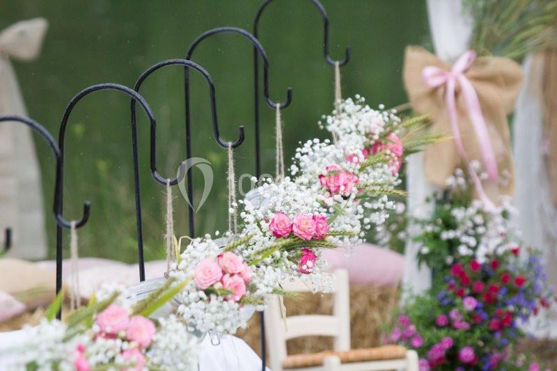 Guirlande de fleurs roses et blanches suspendue à des crochets noirs dans un décor extérieur festif.