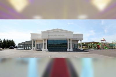 Salle de réception élégante avec tables décorées de nappes blanches, centres de table floraux et éclairage rose.