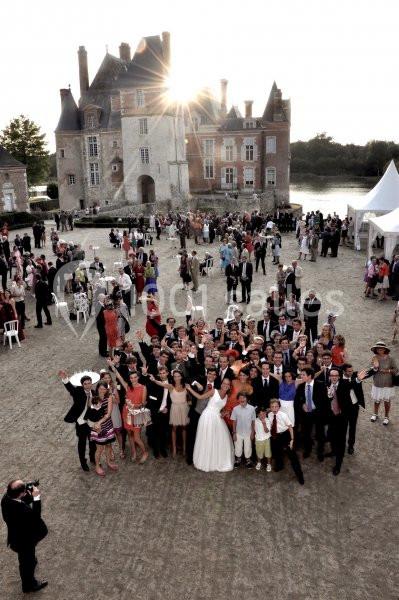 Groupe de personnes posant devant un château historique au coucher du soleil lors d'un événement en plein air.