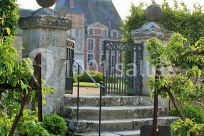 Salle en pierre avec poutres apparentes, tables rondes dressées et décorations lumineuses pour un événement.