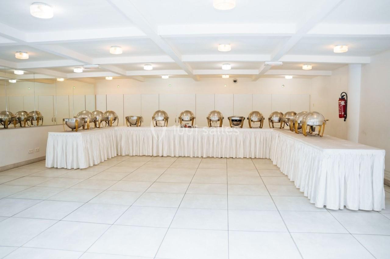 Location salle Viry-Châtillon (Essonne) - Glodie Evènements #6 Salle lumineuse avec des plats en inox alignés sur des tables drapées de nappes blanches, prête pour un buffet.