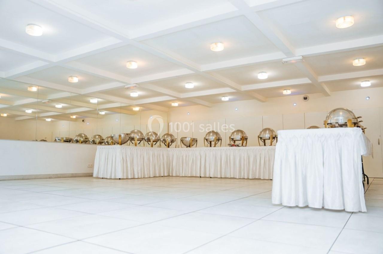 Location salle Viry-Châtillon (Essonne) - Glodie Evènements #7 Salle lumineuse avec un buffet de plats sous cloches argentées, disposé sur des tables recouvertes de nappes blanches.