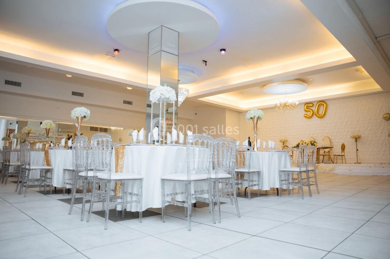 Location salle Viry-Châtillon (Essonne) - Glodie Evènements #9 Salle de réception élégante avec tables rondes dressées, chaises transparentes et décoration florale blanche.
